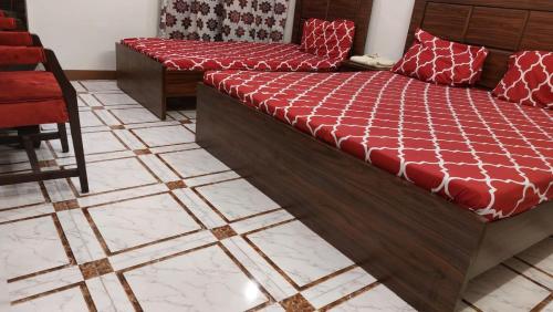 a bedroom with a bed and a chair and tile floors at Gulshan Guest House Gulberg Town in Karachi