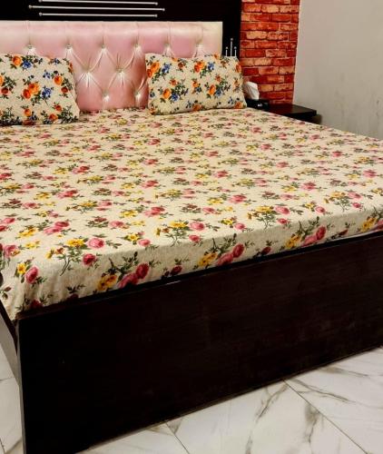 a bed with a pink bed frame with flowers on it at Gulshan Guest House Gulberg Town in Karachi
