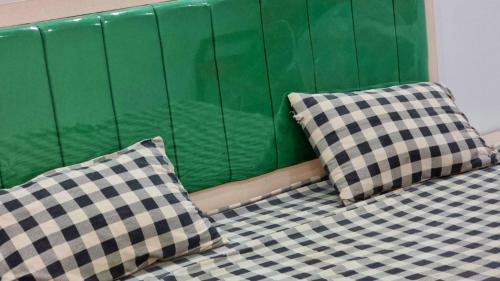 two pillows sitting on a bed with a green wall at Gulshan Guest House Gulberg Town in Karachi