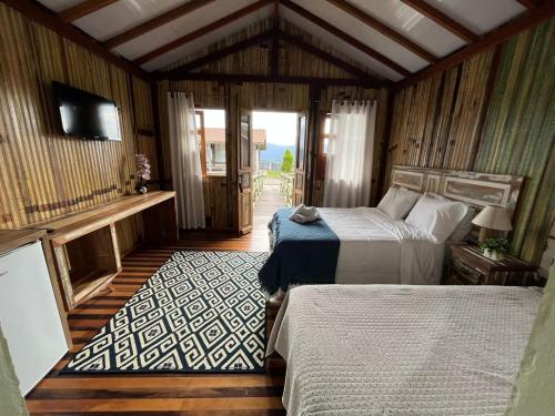 a bedroom with two beds and a television in it at Eco Mirante Hotel in Paulo Lopes