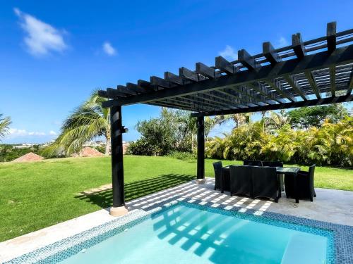 a pergola over a swimming pool with a table and chairs at Ileverde 21 - Private garden Bungalow in Punta Cana