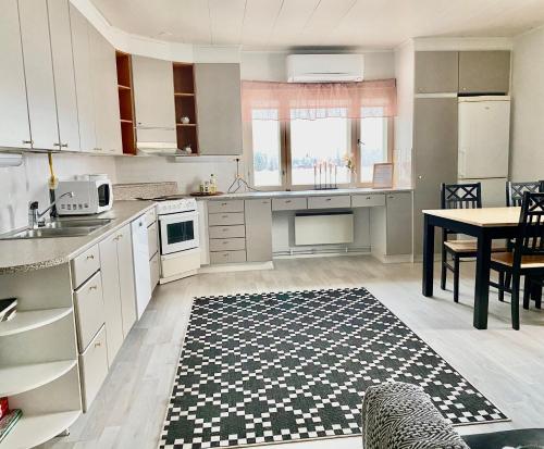 uma cozinha com armários brancos e uma mesa com um tapete em Cozy apartment with sauna em Haapavesi