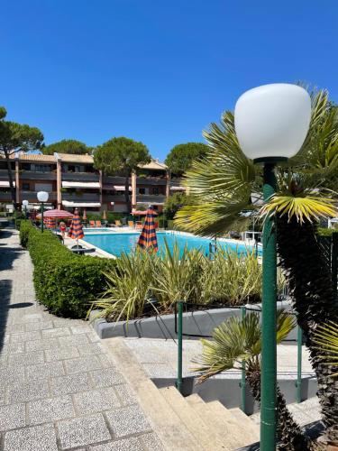 a street light next to a swimming pool with palm trees at Summer House - Appartamento fronte mare in Marcelli