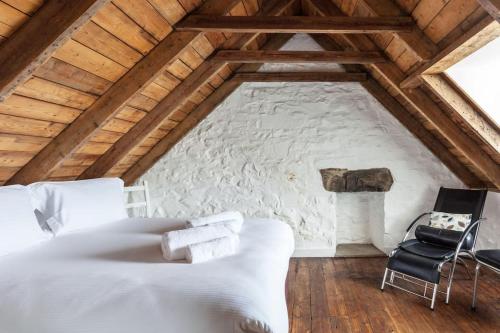 a bedroom with a white bed and a stone wall at Isle of Skye Cottage in Kyleakin