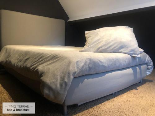 Appartement aan Puyenbroeck في Wachtebeke: سرير مع وسادة بيضاء و اللوح الأمامي أسود