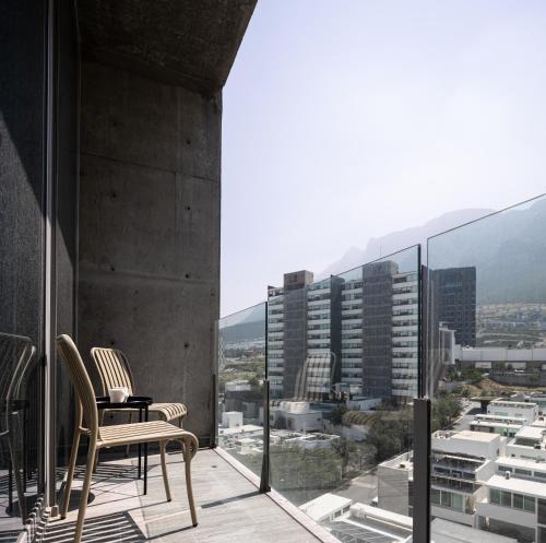 a balcony with two chairs and a view of a city at Cerca de consulado EUA, nuevo, lujoso en Jardín Secreto 503 in Monterrey