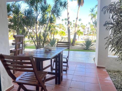 a wooden table and chairs on a patio with palm trees at Stanza Mare Beach Front in Punta Cana
