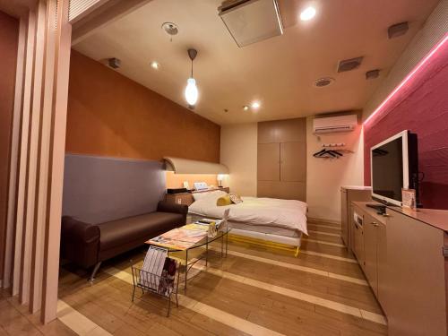 1 dormitorio con cama, sofá y mesa en 旭川ホテルカラーズ-大人専用 en Asahikawa