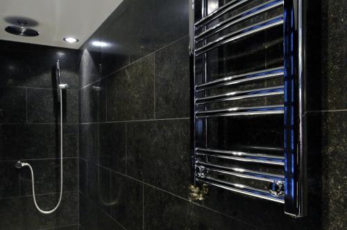 baño con ducha y pared de azulejos negros. en Amsterdam Boutique Apartments, en Ámsterdam