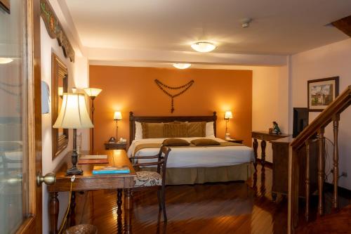 a bedroom with a bed and a table with a lamp at Hotel Patio Andaluz in Quito