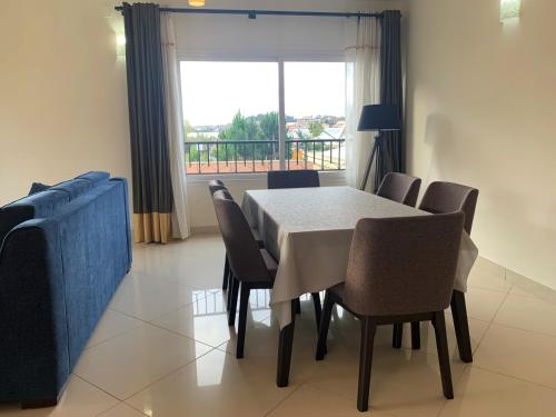 a dining room with a table and chairs and a window at Appartements - Le Paradisier Ambatobe in Antananarivo