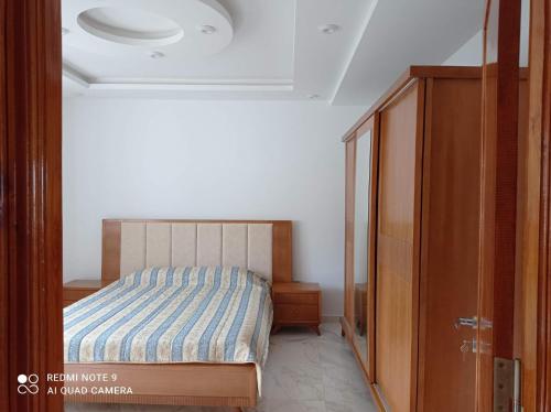 um quarto com uma cama e um armário de madeira em Eline em Rafrāf