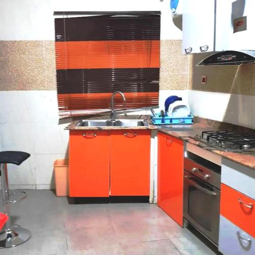 eine orangefarbene Küche mit einer Spüle und einem Herd in der Unterkunft ORCHID House Stylish 3BDR Terrace Duplex Free WiFi DSTV in Lekki