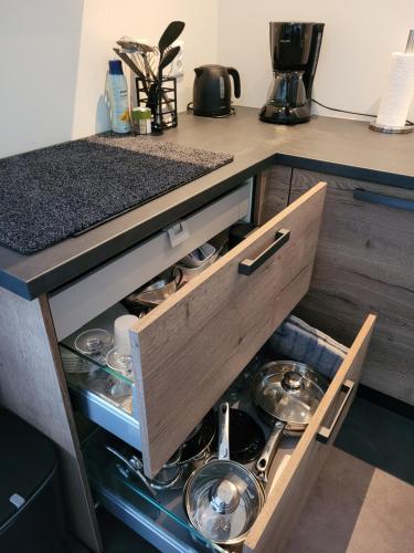 einem Küchenschrank mit einer Schublade voller Geschirr in der Unterkunft Timmershoeve in Vorstenbosch