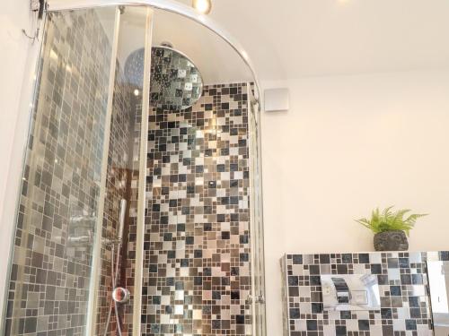 ducha con puerta de cristal y pared de mosaico en Haven en Lytham St Annes