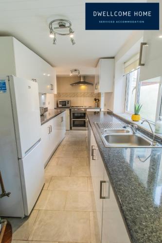 a kitchen with white cabinets and a counter top at Entire 8 Ensuite Bedroom Coastal Holiday Home Townhouse, Free Parking, Fully Equipped Kitchen, Dining Room & Lounge, Perfect for Family Gatherings, Long Term Contractor, Relocation, etc Stays, 20 mins to Sunderland & Newcastle, See our Site for Assurance in South Shields