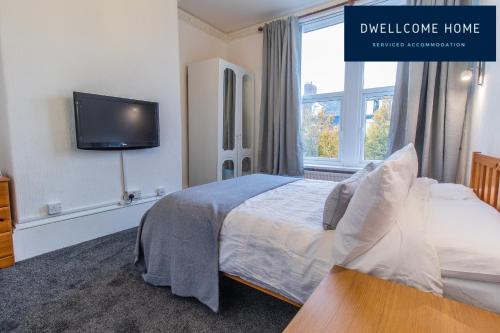 um quarto com uma cama e uma televisão na parede em Dwellcome Home Ltd Spacious 8 Ensuite Bedroom Townhouse - see our site for assurance em South Shields