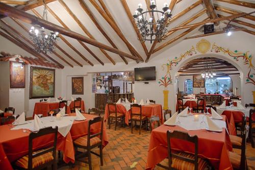 un restaurante con mesas y sillas rojas y TV en Munay Wasi Inn, en Cusco