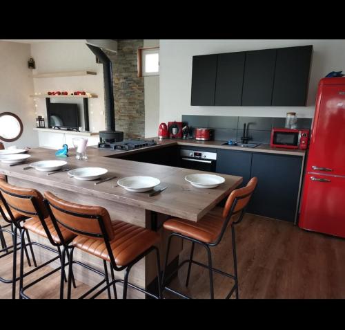 a kitchen with a wooden table with chairs and a red refrigerator at A quelques pas du moulin blanc in Brest