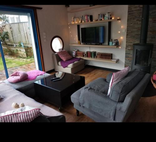 uma sala de estar com dois sofás e uma televisão em A quelques pas du moulin blanc em Brest