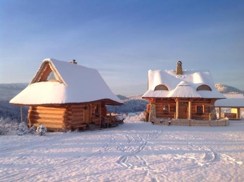
a house with a snow covered roof and a snow covered cabin at Osada Beskidzka in Zawoja
