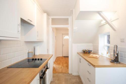 una cucina con armadi bianchi e ripiano in legno di 3 Bed House/Garden/Wi-Fi/Parking/Central Location a Stoughton