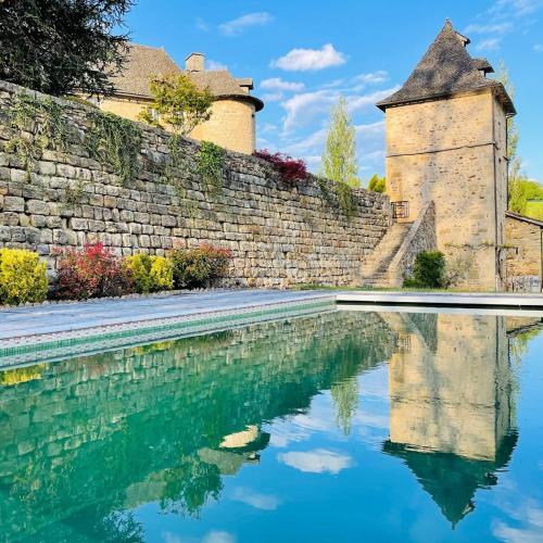 une piscine d'eau à côté d'un mur de briques et d'un bâtiment dans l'établissement Castle in the beautiful French countryside with all modern comfort, à Terrou