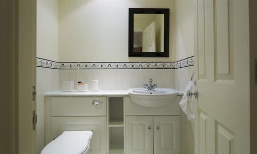 a bathroom with a sink and a toilet and a mirror at Merewood Lodge in Ambleside