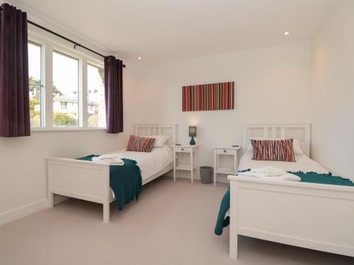 a bedroom with two beds and a window at 4 Court Terrace, Hillfield Village in Dartmouth