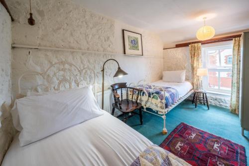 a bedroom with two beds and a chair in it at Lifeboat Cottage by Big Skies Cottages in Brancaster