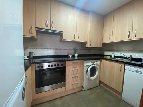 a kitchen with wooden cabinets and a washer and dryer at APARTAMENTO EN CENTRO PUEBLO in Ribes de Freser