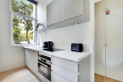 une cuisine blanche avec un évier et une fenêtre dans l'établissement Flat with Terrasse - 1BR-4P - Eiffel Tower, à Paris