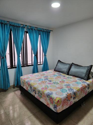 1 dormitorio con 1 cama con cortinas azules en Espléndido apto completo en el centro de Pereira, en Pereira