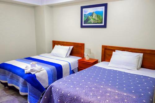 a bedroom with two beds and a picture on the wall at Hotel Los Andes Boutique in Huaraz