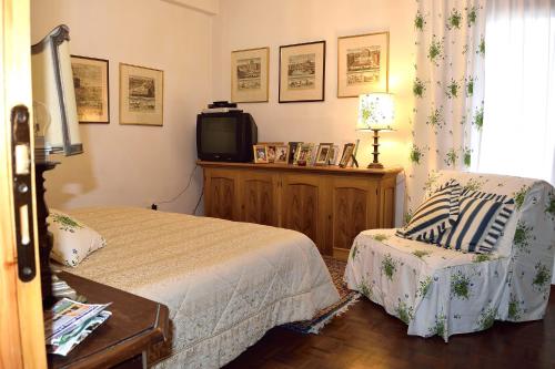 a bedroom with a bed and a tv and a chair at Casa Rosa in Pescasseroli