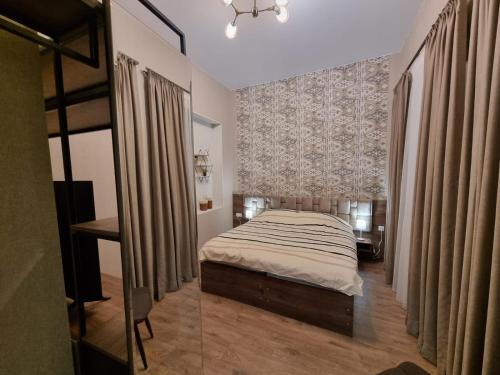 a bedroom with a bed and a desk and curtains at Nino's Cosy Apartment in Kutaisi