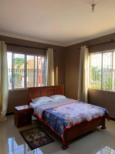 a bedroom with a bed and two windows at Dodoma, Tukae Inn in Dodoma