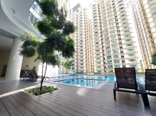 a pool in a building with a palm tree and chairs at The Florence at McKinley Hill in Manila