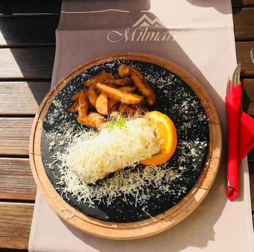 um prato de comida com carne, queijo e uma laranja em Milmari - Breakfast and pool em Kopaonik