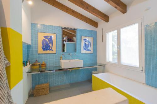 een badkamer met blauwe tegels, een bad en een wastafel bij Casa Algarrobo in Jávea
