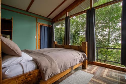 a bedroom with a bed in a room with windows at Above the Gulf, Vacation House in Monteverde Costa Rica