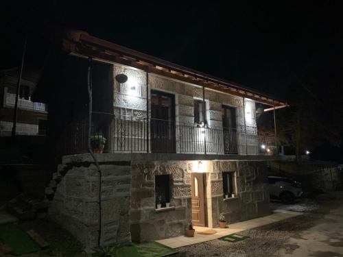 un edificio in pietra con balcone di notte di CASA TIO HERMINIO a O Irixo