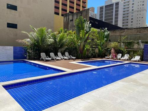 una piscina con sedie a sdraio accanto a un edificio di Guarujá, Pintangueiras, Flat a Guarujá