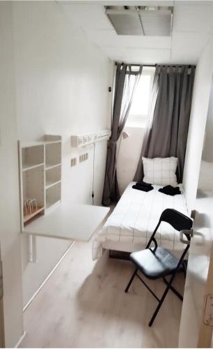 Habitación blanca pequeña con cama y silla en Bjergvænget 16, 2400 København, en Copenhague