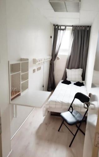 a small white room with a bed and a chair at Bjergvænget 16, 2400 København in Copenhagen