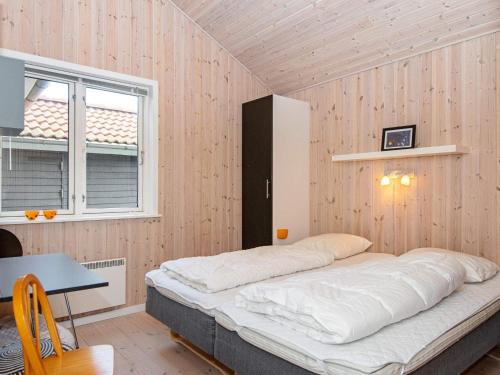 a bed in a room with a table and two windows at Three-Bedroom Holiday home in Ulfborg 16 in Fjand Gårde