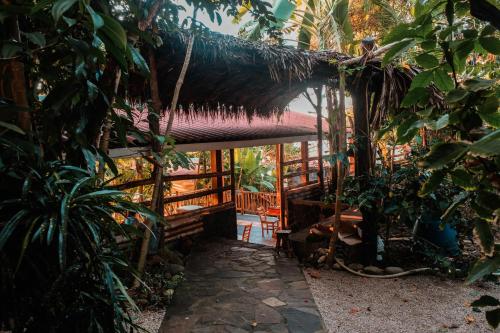 a hut with a thatched roof in a forest at El Marabu Chill'n Surf in Aposentillo