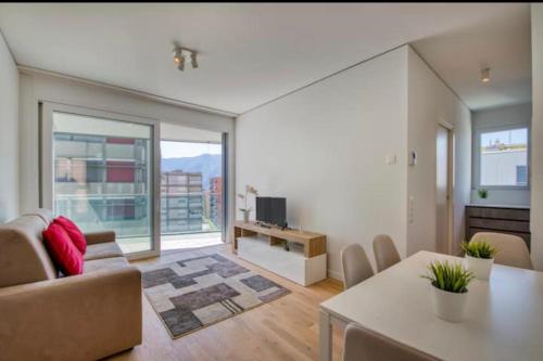 sala de estar con sofá, mesa y TV en 5 Rent Apartments Lugano Station en Lugano