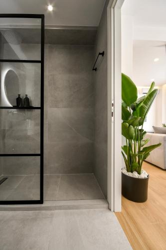 a glass shower door in a bathroom with a plant at Luxury Downtown Apartment C1 in Thessaloniki