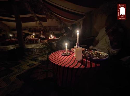 einen Tisch mit zwei Kerzen und einem Teller Essen in der Unterkunft Gite Agham Azegagh - Timimoun 